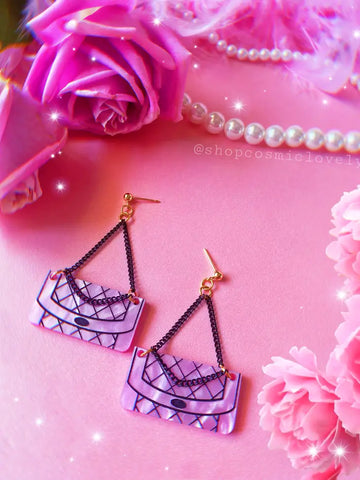 Earrings against a pink background with floral and feather accents