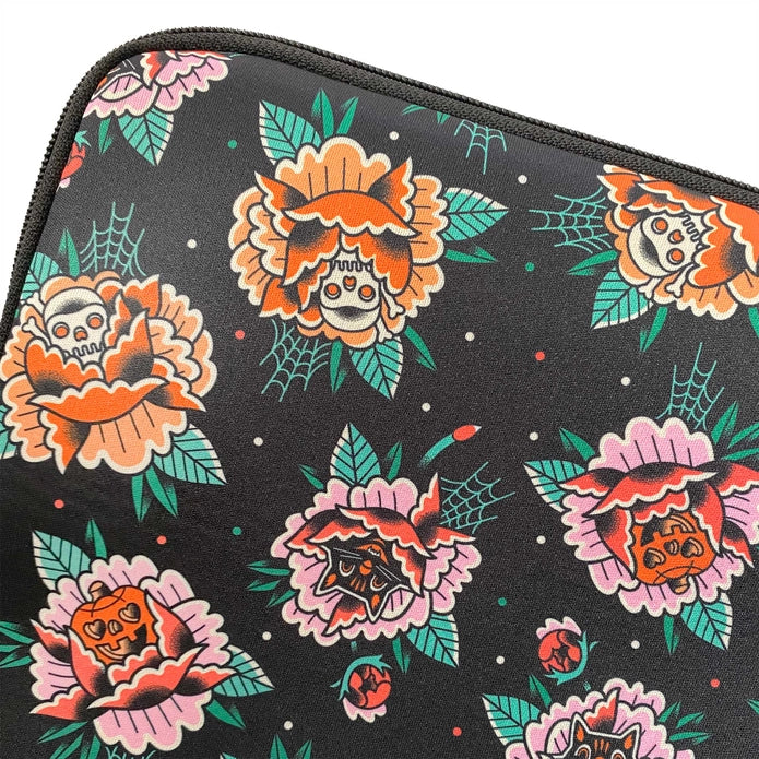 Close up of the design that is on the front of the laptop sleeve which includes jack o lanterns, black cats, and skulls inside of pink and orange peonies