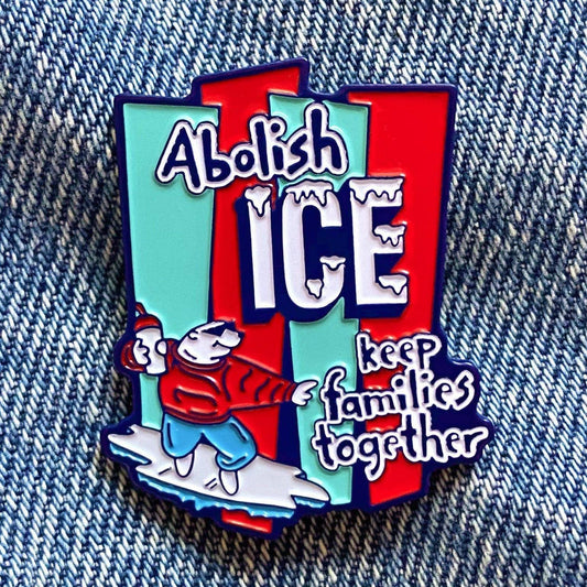 Red and blue enamel pin featuring the text 'Abolish ICE keep families together' with a cartoon polar bear surfing on ice.