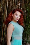 Model with bright red hair showcasing a close up of the side of the dress against a bamboo forest background