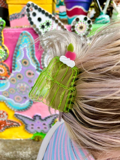Transparent green jello cake hair claw in blonde hair against a colorful background.