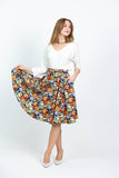 Model with hand holding one side of skirt up against a white background