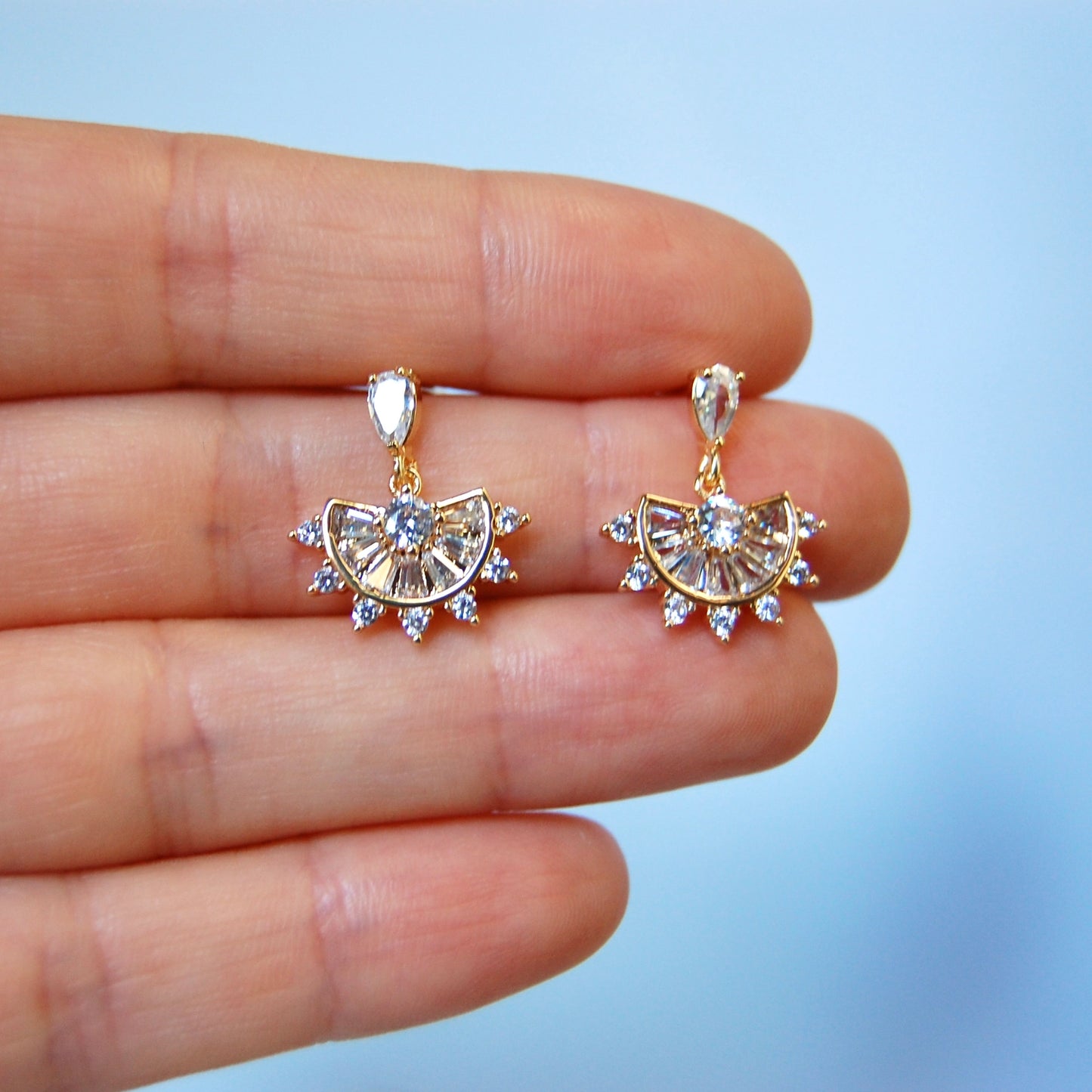 Earrings in a hand model against a light background