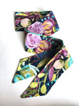 This photo shows the scarf laid our to showcase the flowers. Flowers are purple and yellow against a dark blue background