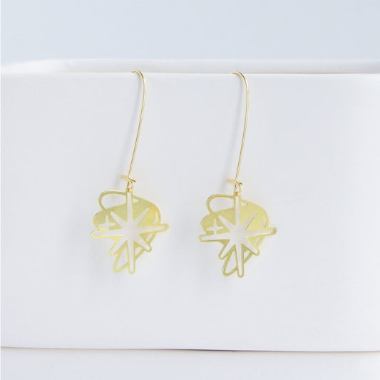 This photo showcases an up close look at the Starburst earrings in gold. They are hanging from a white item