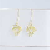 This photo showcases an up close look at the Starburst earrings in gold. They are hanging from a white item