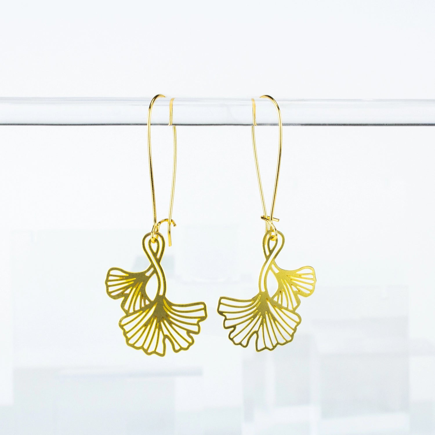 This photo shows a close up of the earrings. Earrings are a gold color with long hooks for the earrings. Ginko Leaves are also in gold