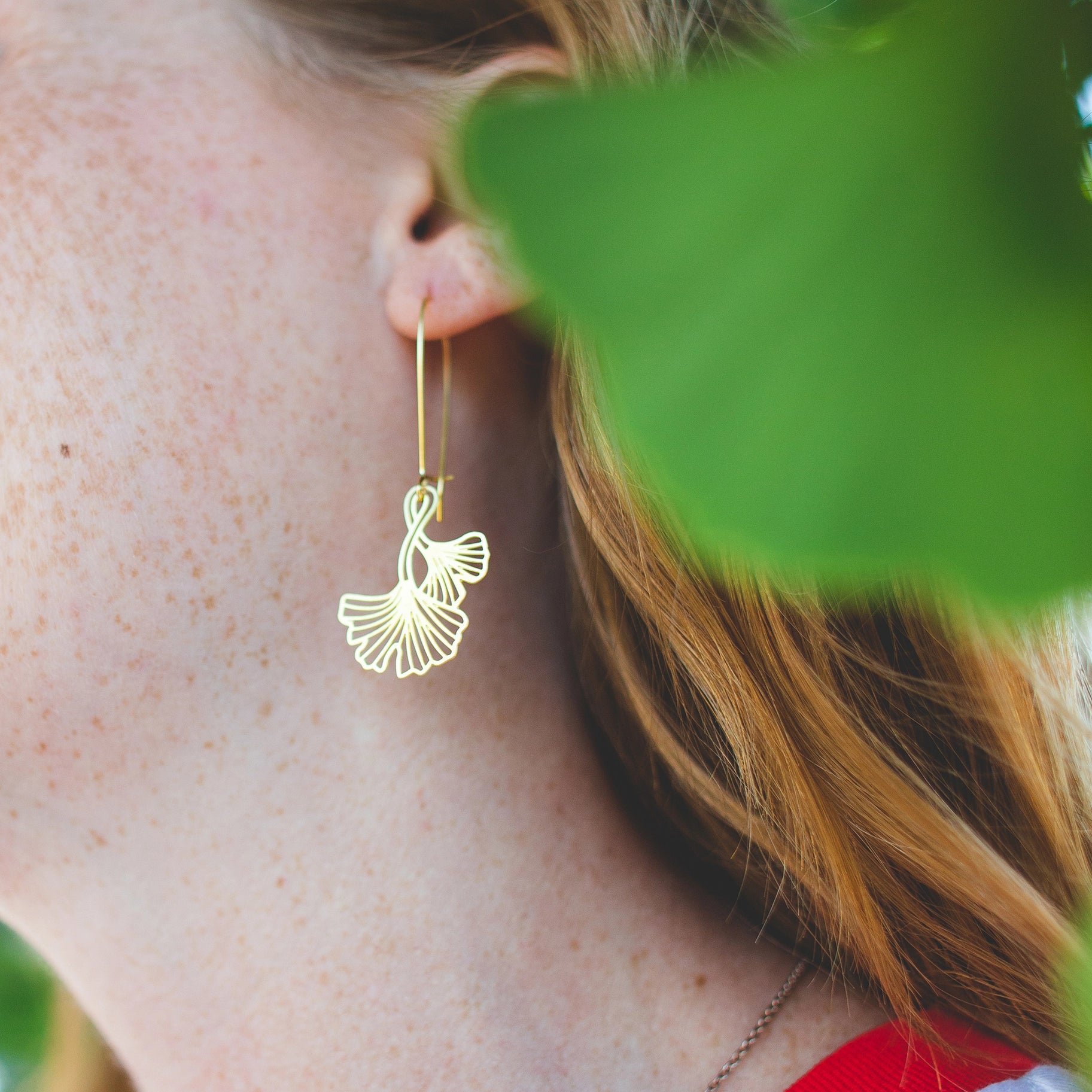 This photo shows the earrings being worn by a white model with ginger hair, and freckles. Earrings are dangling about 2 inches from the ear