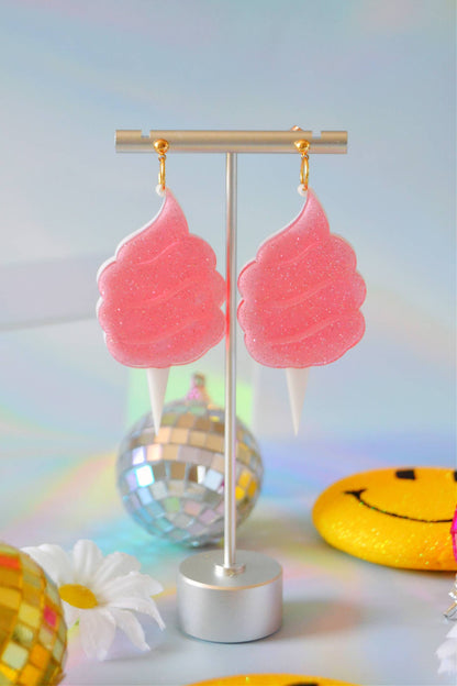 Earrings hanging from display against a light background