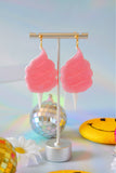Earrings hanging from display against a light background
