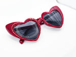 Deep red heart sunglasses. Hearts have the outside half is higher than the inside. Has black lenses. Photo shows glasses closed