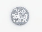 A rounk phone grip with silver holographic glitter. Has "true crime and caffeine" in white lettering