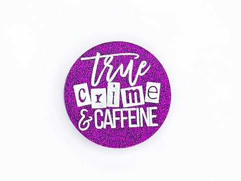 A round purple glitter phone grip with "true crime and caffeine" in white lettering
