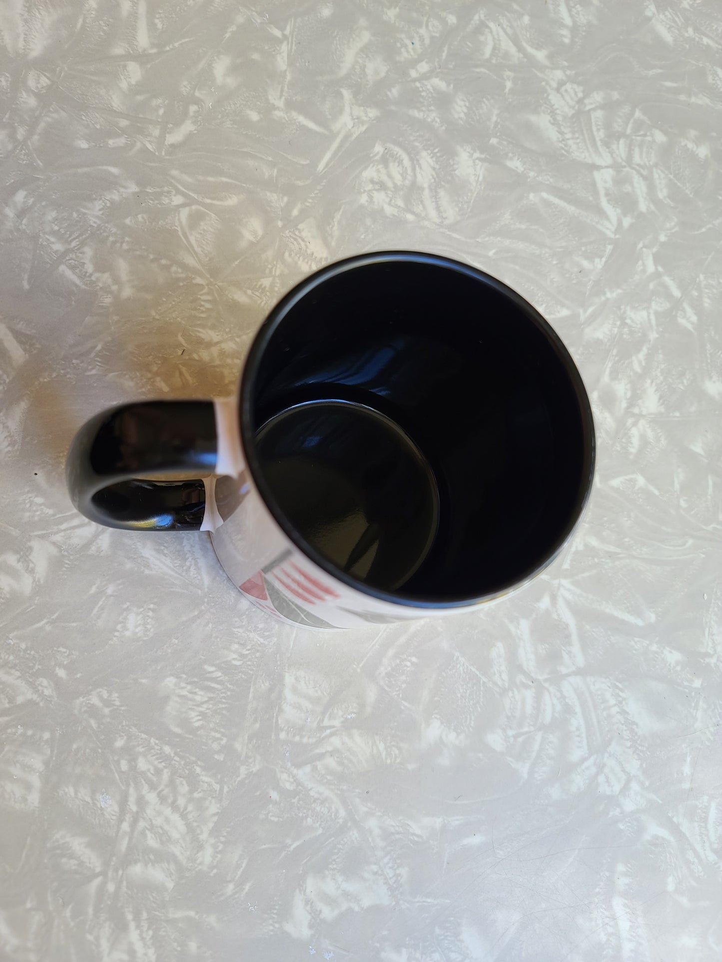 1950s mid century modern style lotus flower with green outer petals and red inner petals against a white background. Mug has black coloring inside of the mug, and a black handle