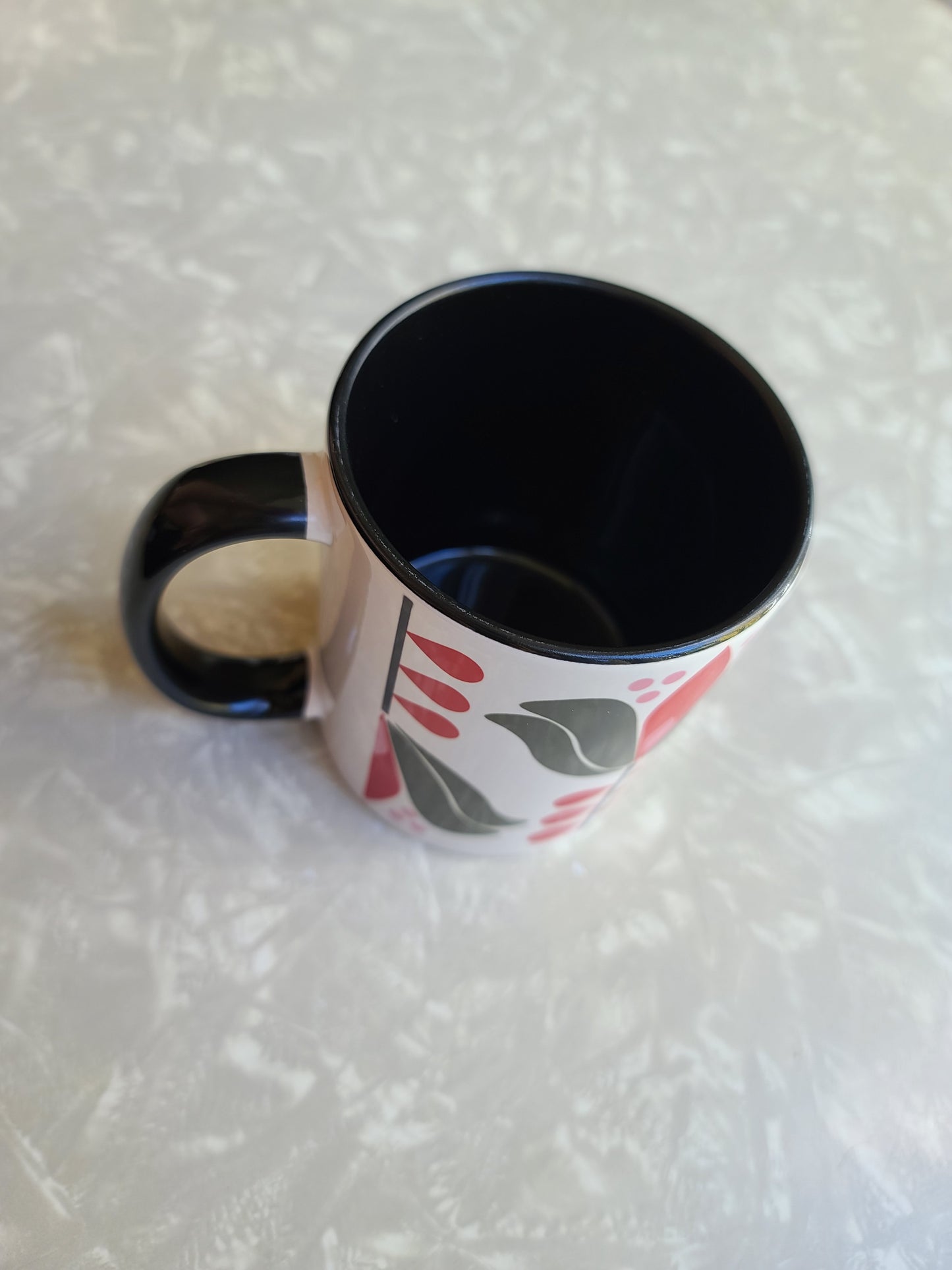 1950s mid century modern style lotus flower with green outer petals and red inner petals against a white background. Mug has black coloring inside of the mug, and a black handle