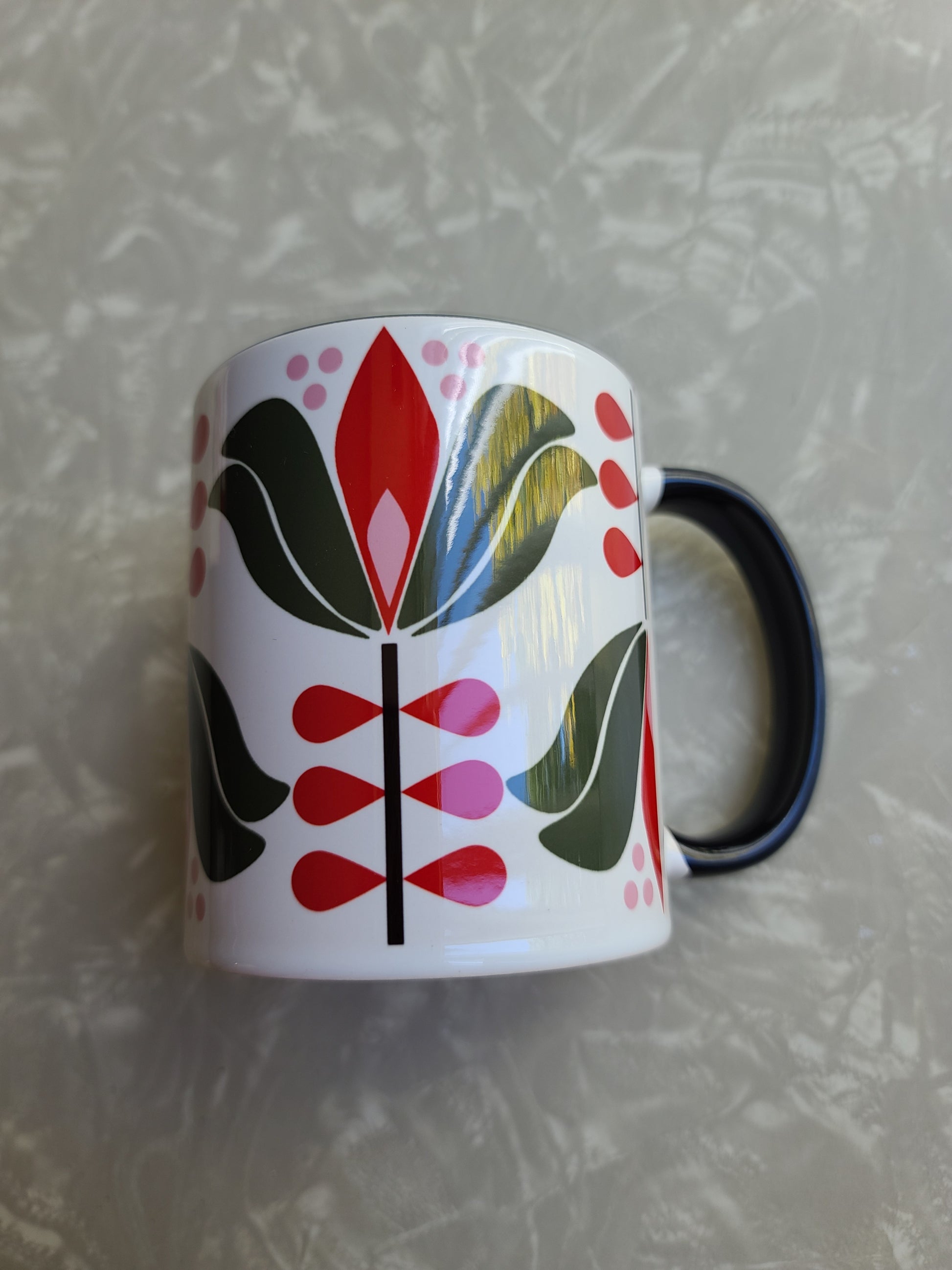 1950s mid century modern style lotus flower with green outer petals and red inner petals against a white background. Mug has black coloring inside of the mug, and a black handle