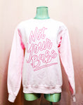 Light pink sweater with dark pink lettering saying "Not your babe" lettering is an outline lettering. Photo shows the sweater on a silver mannequin with a pink background
