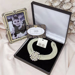 Necklace and earring set in gift box next to photo of Audrey Hepburn