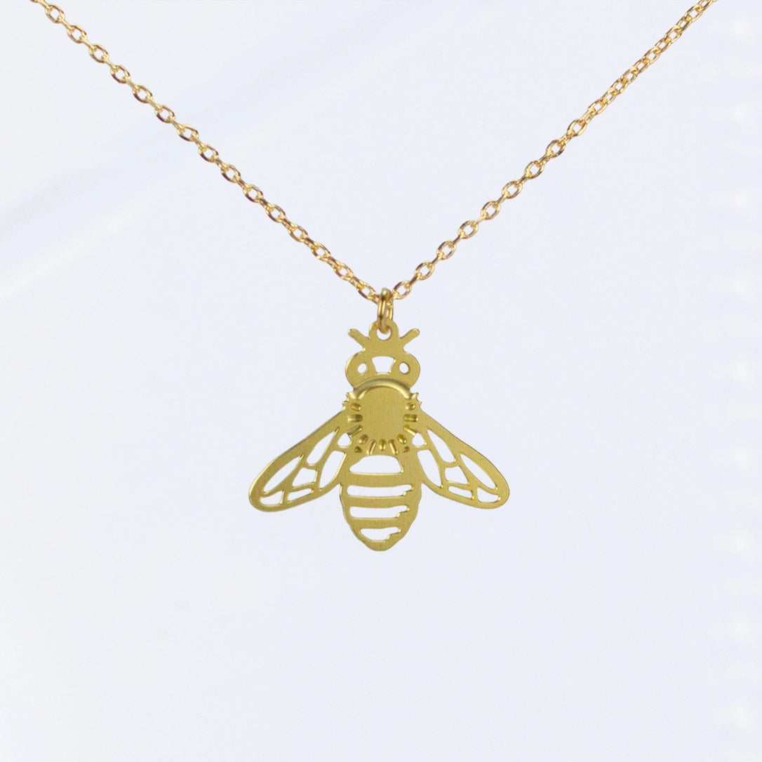 This photo shows an upclose look at the necklace. Necklace is gold in color, and the bee is a single gold colored bee