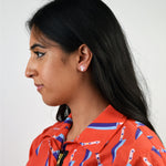 This photo shows a POC model with black hair wearing the earrings. Earrings are small studs, and sit within the size of the earlobes