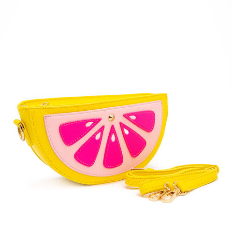 Purse is shown against a white background. Purse is a half of a grapefruit. Purse is yellow with a light pink center, and dark pink accents, and a yellow strap