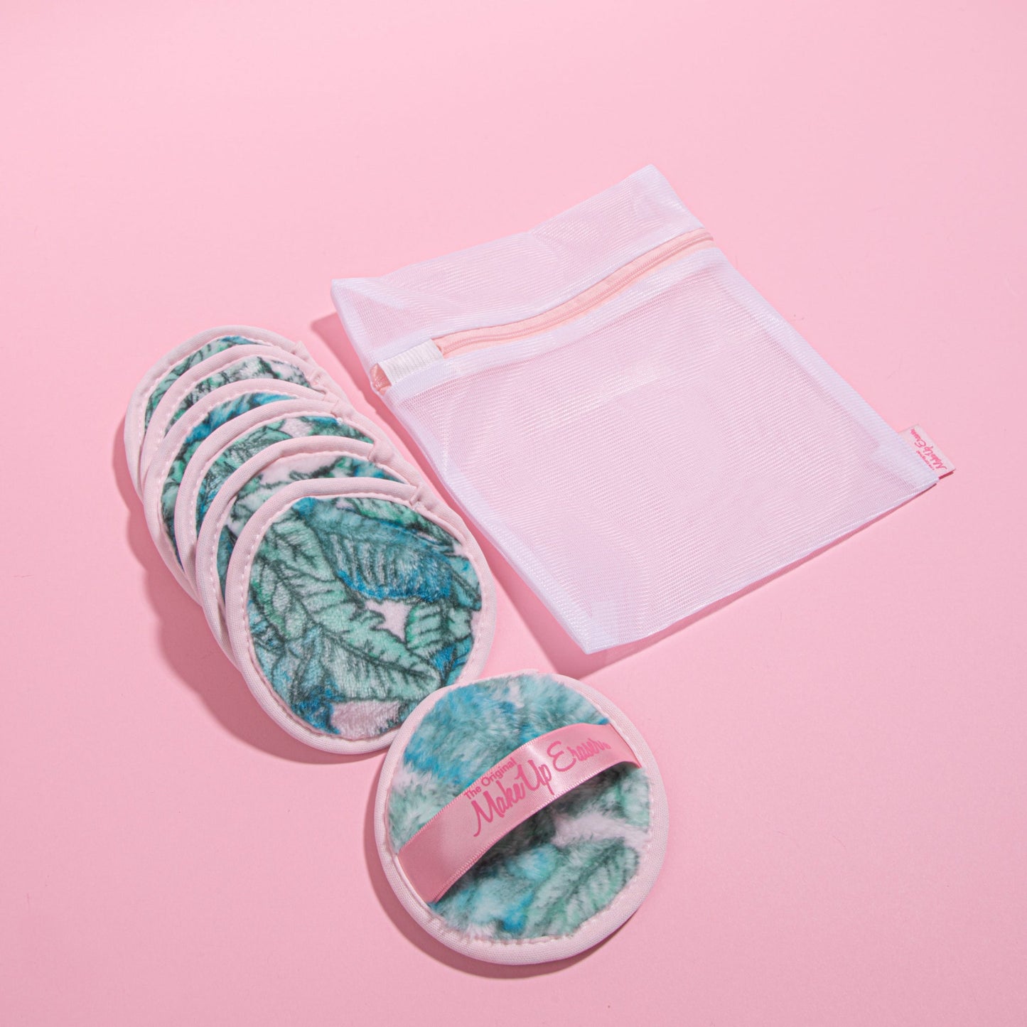 Makeup erasers and wash bag against a pink background