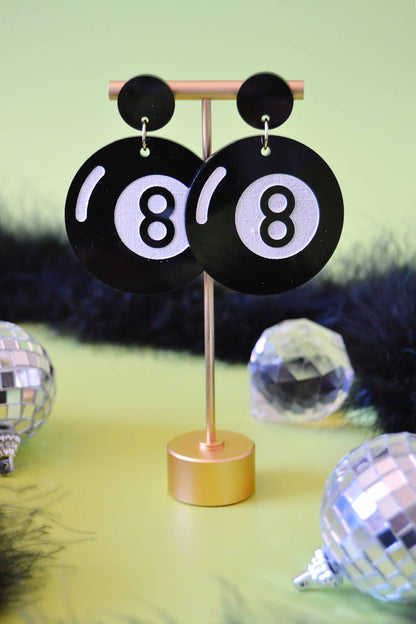 Earrings hanging from display with green background