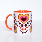This mug has an orange, dark maroon, yellow, and pink coloring. Hearts have alternating colors inside of each other and are on a pink stem. Each heart flower alternates being upright and upside down with pink, maroon, and yellow dots as leaves flowing between each heart flower. Mug handle, and inside coloring is orange