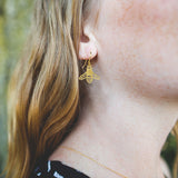 This photo shows the earring on a white model with ginger hair. Earrings are gold in color