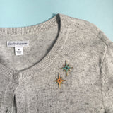 This photos shows both colors the pin comes in on a light great sweater to showcase how it can be styled