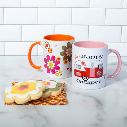 This photo shows the mug with our Groovy Florals Mug. Both mugs are set next to floral cookies.