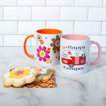 This photo shows the mug with our Groovy Florals Mug. Both mugs are set next to floral cookies.
