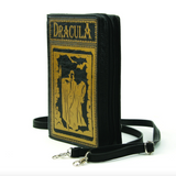 Black vinyl rectangle shaped purse with gold detailing of Dracula with a victim in a cave like setting. Cave features a skull, wall sconce, a bat, and a spider. DRACULA in big bold gold letters across the top. This photo shows the bag from a side view with the zipper, and the black vinyl strap