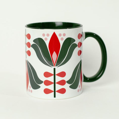 1950s mid century modern style lotus flower with green outer petals and red inner petals against a white background. Mug has black coloring inside of the mug, and a black handle