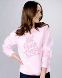 Light pink sweater with dark pink lettering saying "Not your babe" lettering is an outline lettering.  Photo show a brunette white female presenting person wearing it
