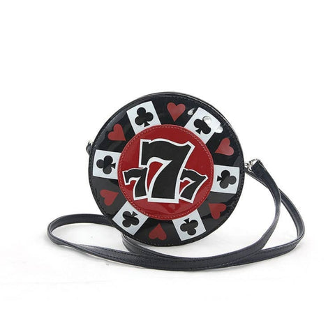 Circular vinyl purse with 3 7s in differing heights in the middle overlaying a red circle. The outer edge of the red circle has red hearts on a black background, and black clubs on a white background alternating around the red circle. Photo also showcases the thin black vinyl strap
