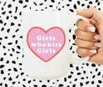 Photo shows an upclose look at the mug. Mug is white with a pink heart. Pink heart has the phrase "Girls who kiss girls" in a white font