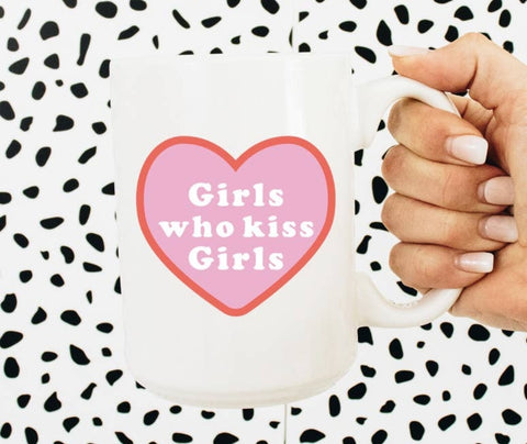Photo shows an upclose look at the mug. Mug is white with a pink heart. Pink heart has the phrase "Girls who kiss girls" in a white font