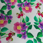 This photo shows a close up view of the dress pattern. Pattern is purple and pink flowers with green leaves on a white background