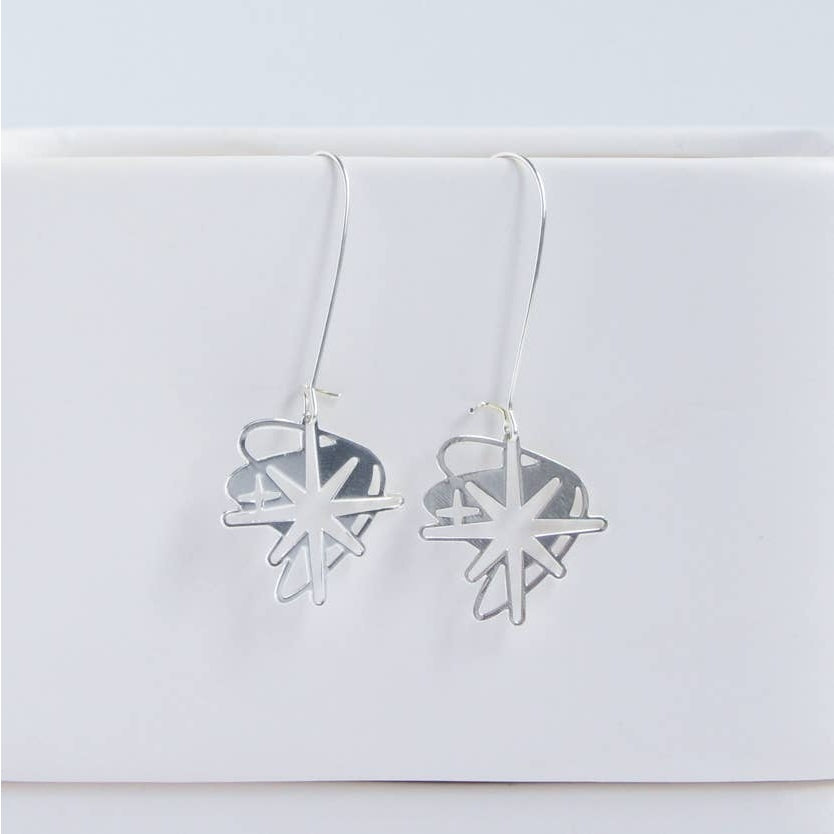 This photo showcases the Starburst earrings against a white background. Earrings are hanging from a white item