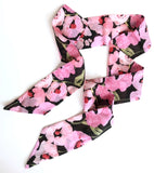 This photo shows the scarf out of the package and unfolded. Scarf has pink poppies against a black background