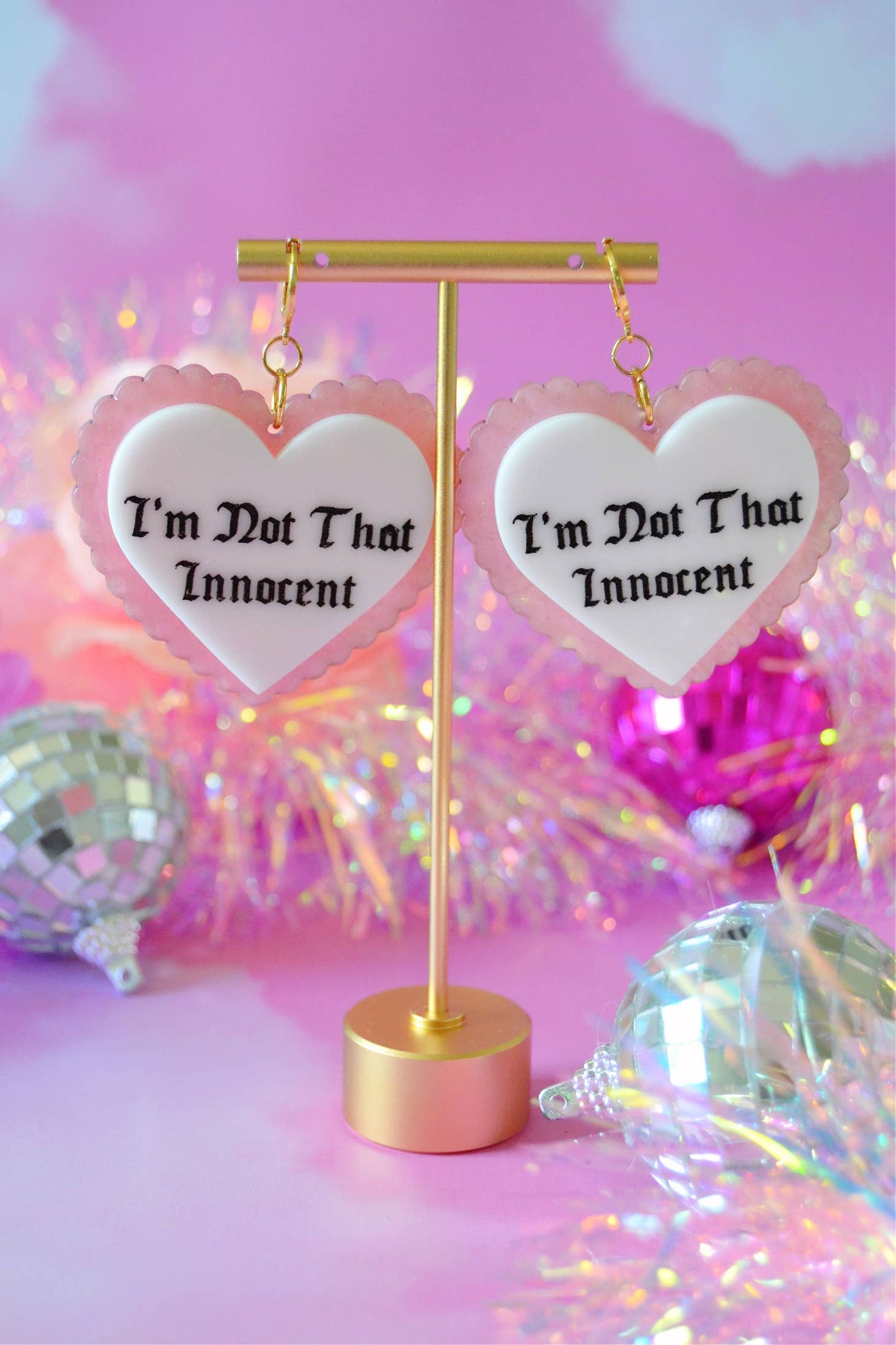 Earrings hanging from display against a pink background